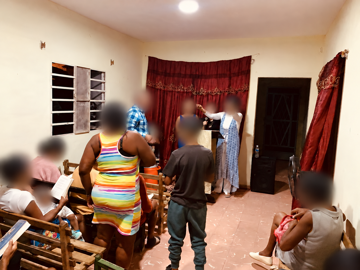 A community gathering indoors, with all faces blurred for privacy