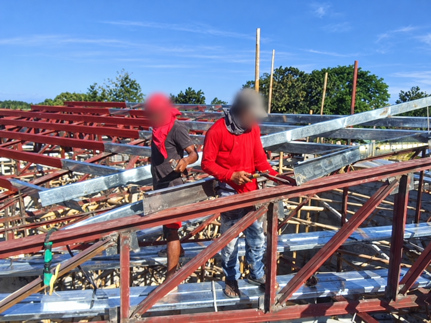 Roof framing under construction, with workers’ faces blurred